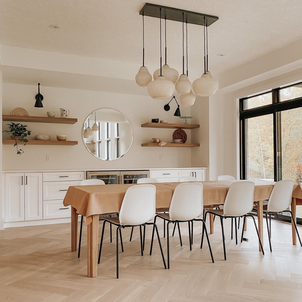 Dining area with a wooden table, white chairs, and floating wall-mounted shelves.