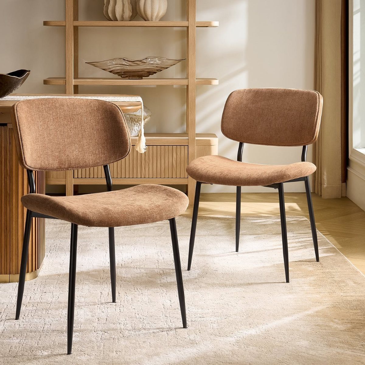 Tan velvet dining chairs with curved backs and thin black metal legs.