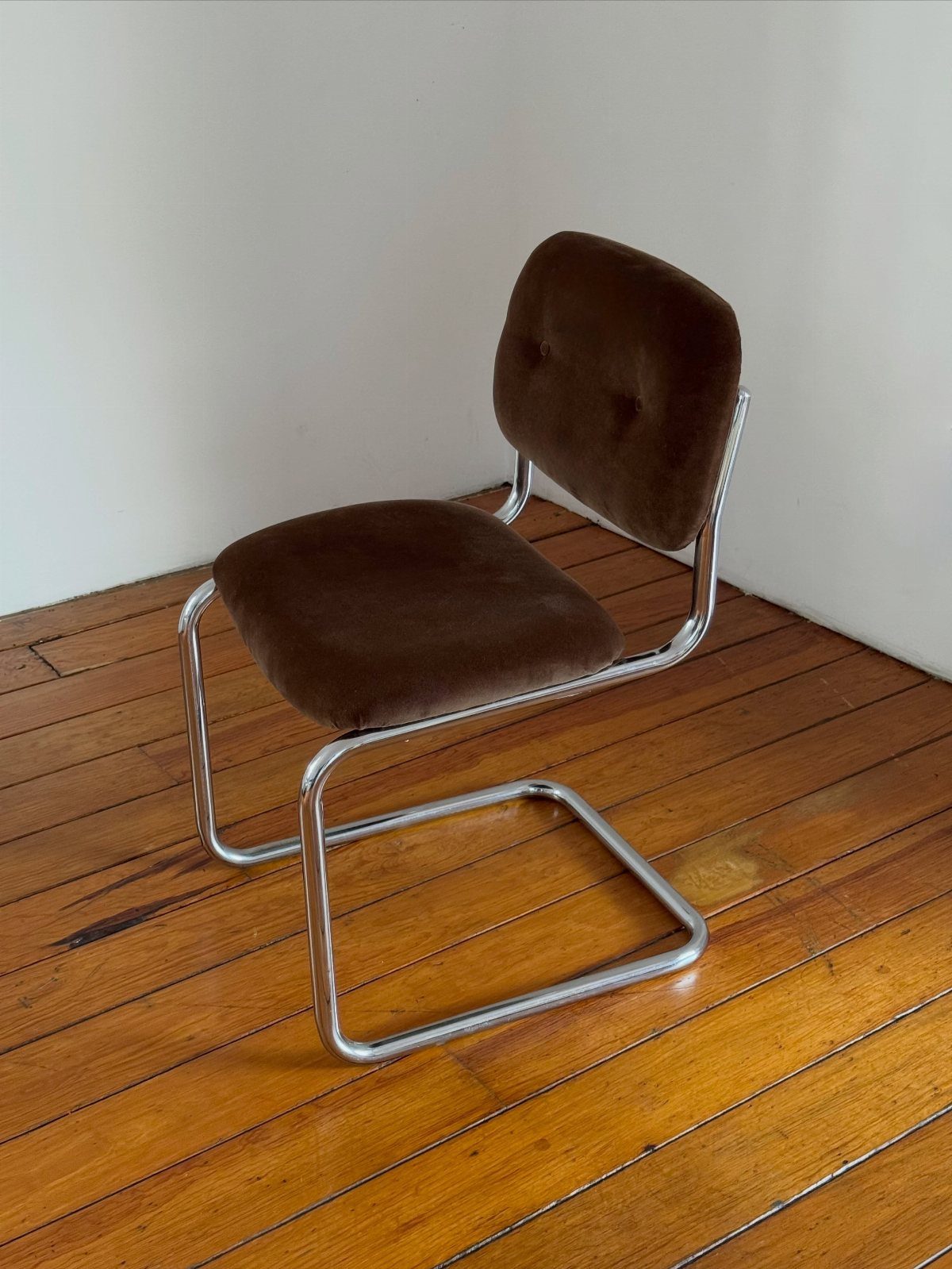 Tan velvet chair with a chrome tubular frame on a wooden floor.