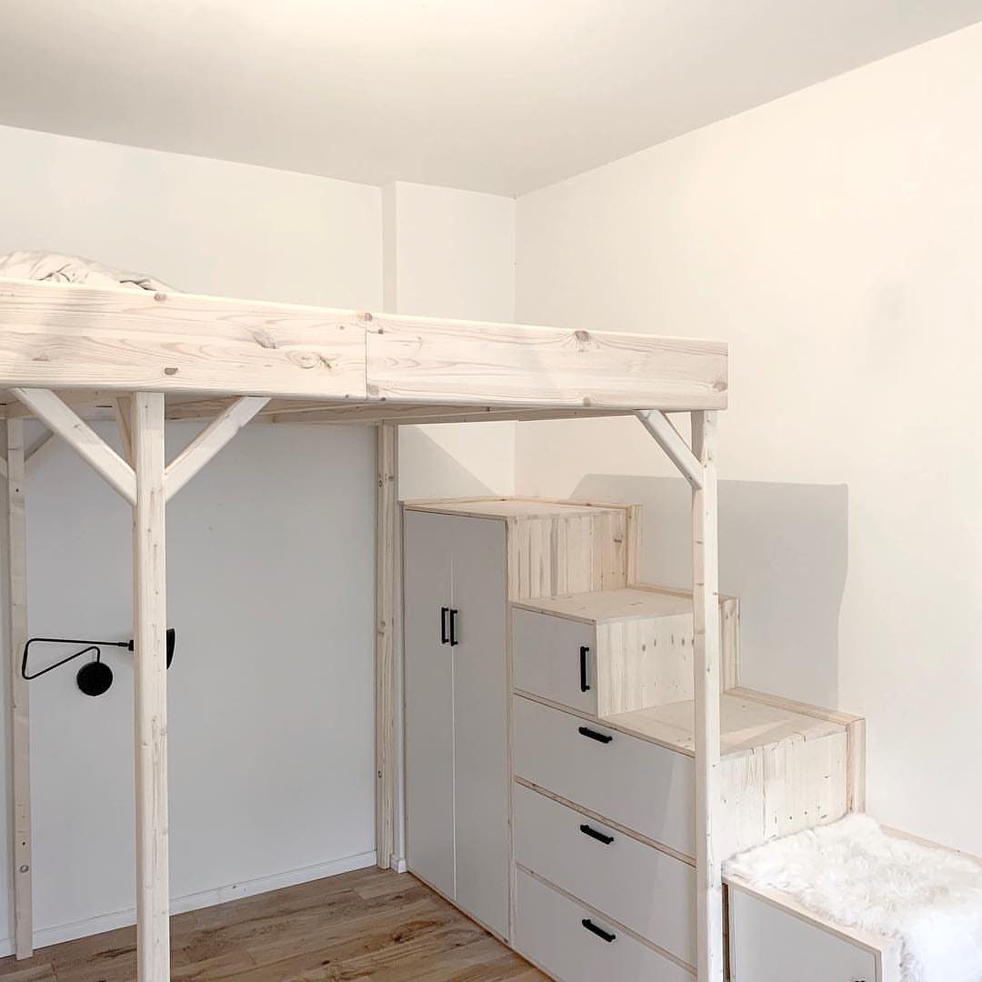 Natural pine wood loft bed frame with white storage drawers and wardrobe below.