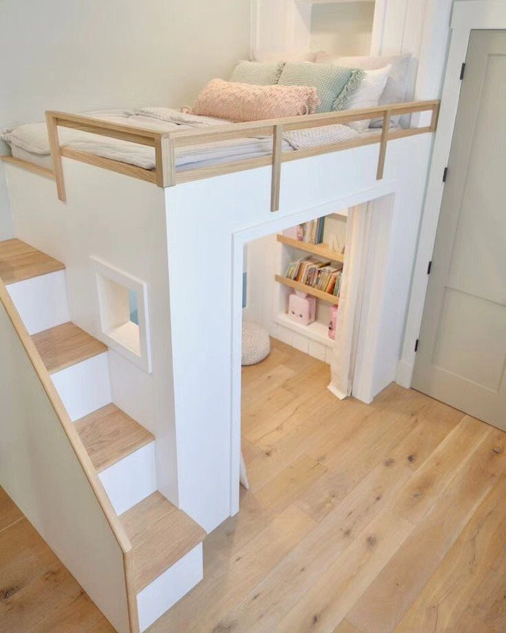 White loft bed with wooden stairs and a reading nook underneath.