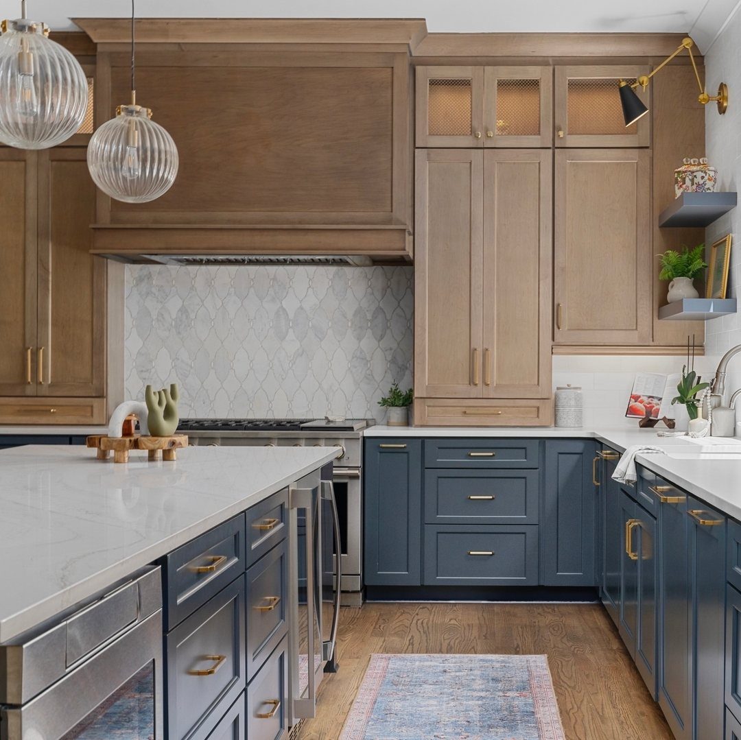 Navy blue lower kitchen cabinets paired with light brown wood upper cabinetry and hood.