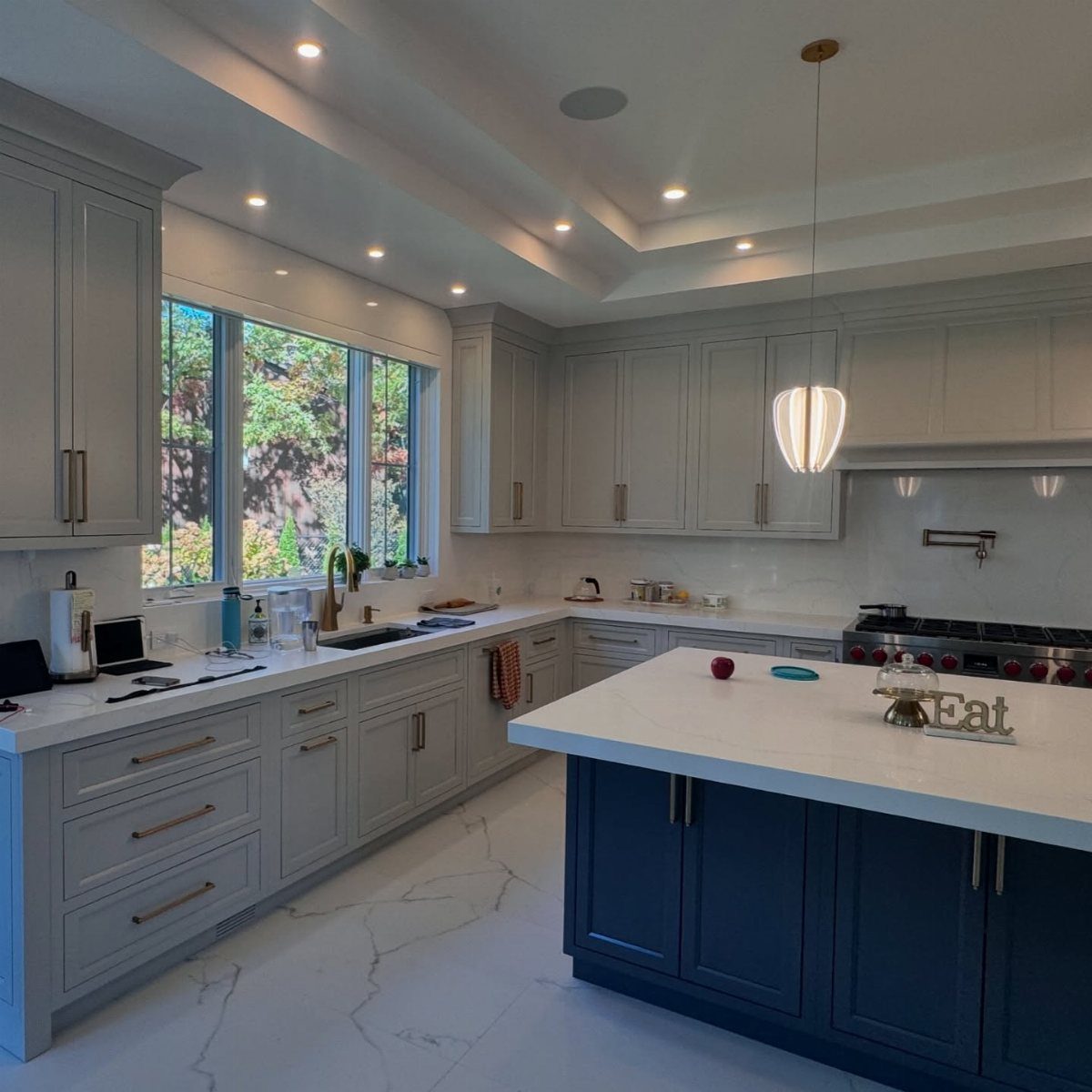 Modern kitchen with light grey perimeter cabinets and a navy blue center island.