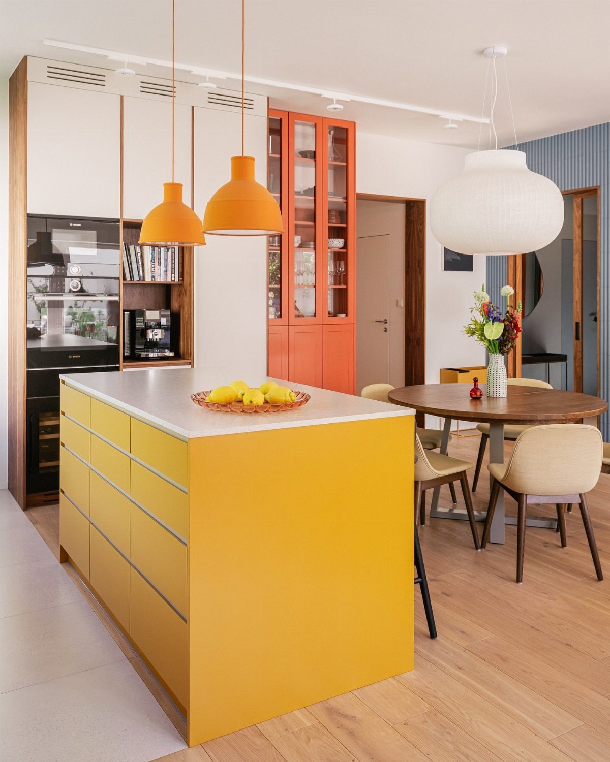 Yellow kitchen island and orange cabinets in a bright, modern open-concept kitchen.