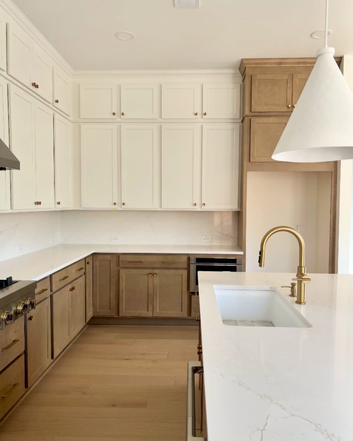 White upper cabinets and blond wood lower cabinets in a modern bright kitchen.