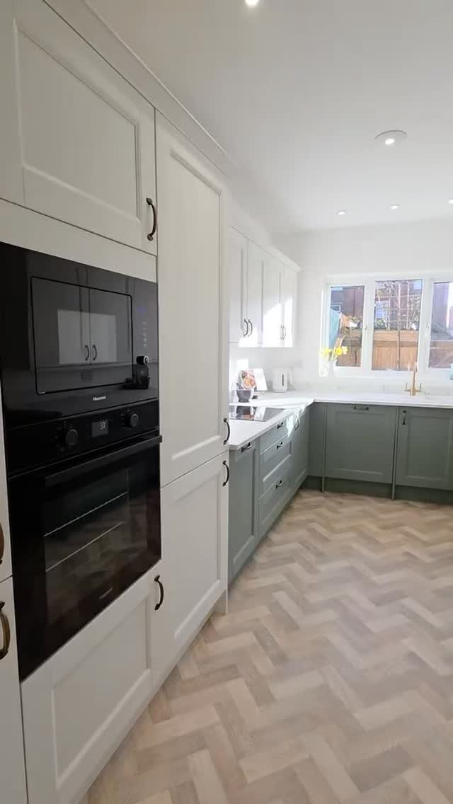White upper cabinets and sage green lower cabinets in a modern kitchen setting.