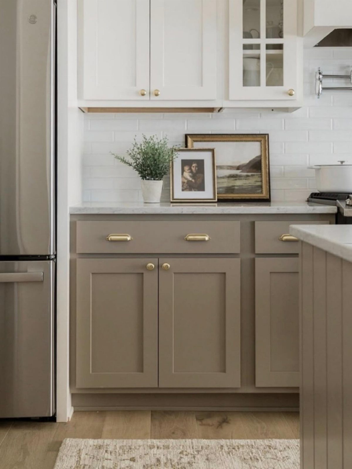 Two tone kitchen cabinets with white uppers and taupe lowers and gold hardware.