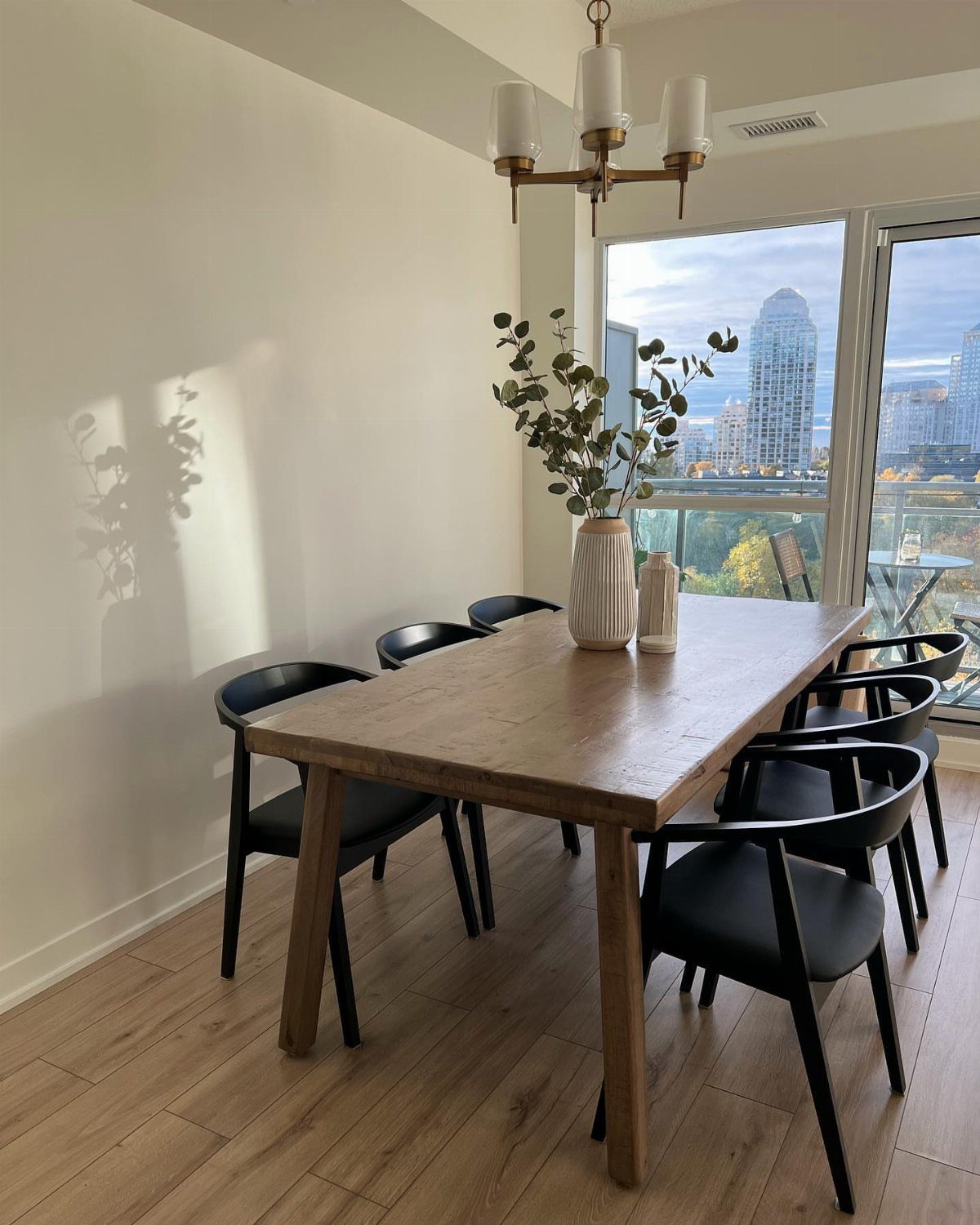 Black curved-back dining chairs surrounding a rectangular walnut table in a bright room.