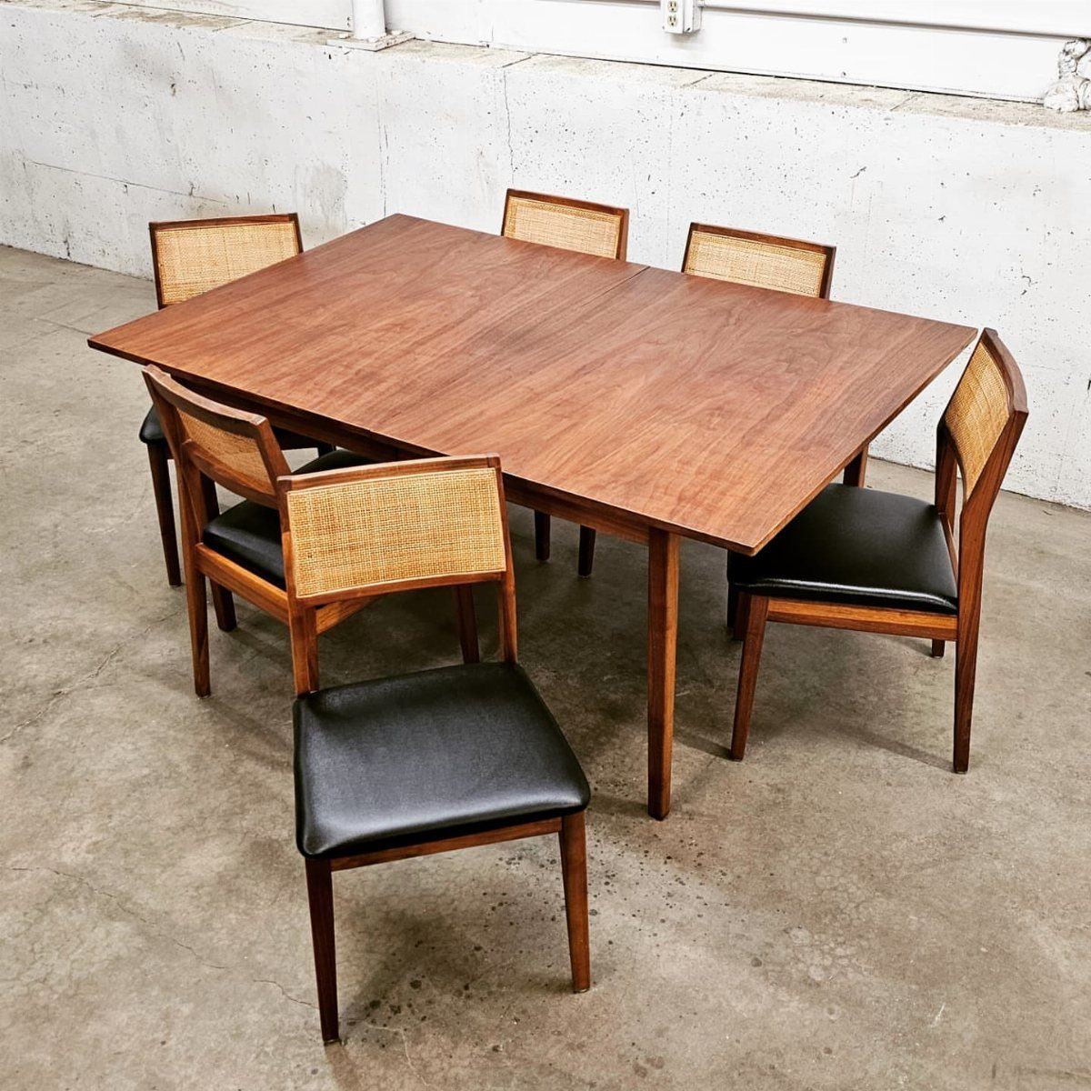 Book-matched walnut dining table with four mid-century modern cane back chairs.