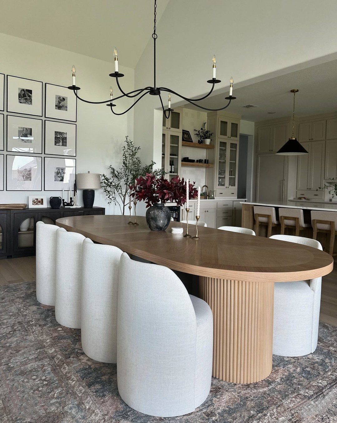 Oval walnut dining table with a fluted pedestal base and cream upholstered chairs.