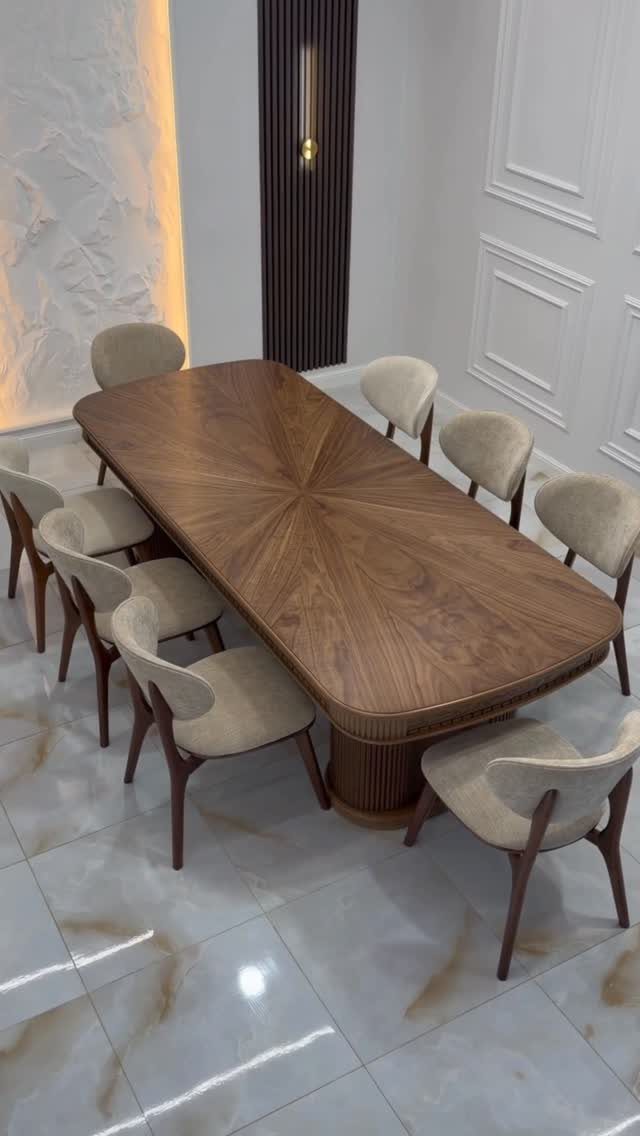 Walnut dining table with fluted base and six cream upholstered chairs on marble floor.