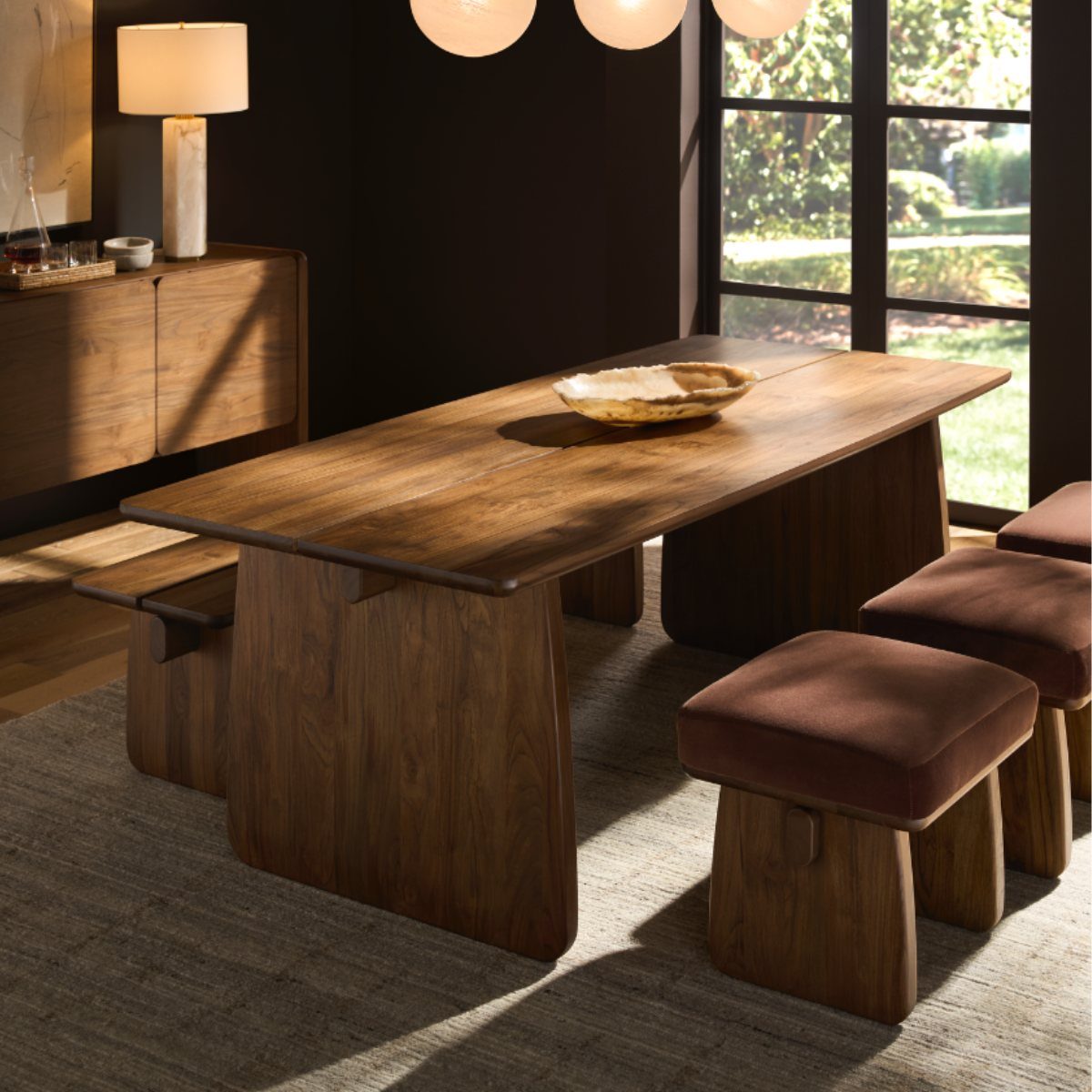 Walnut dining table with matching upholstered benches and a coordinating wooden sideboard.