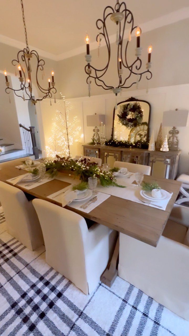 Walnut dining table with a festive greenery centerpiece and white upholstered chairs.