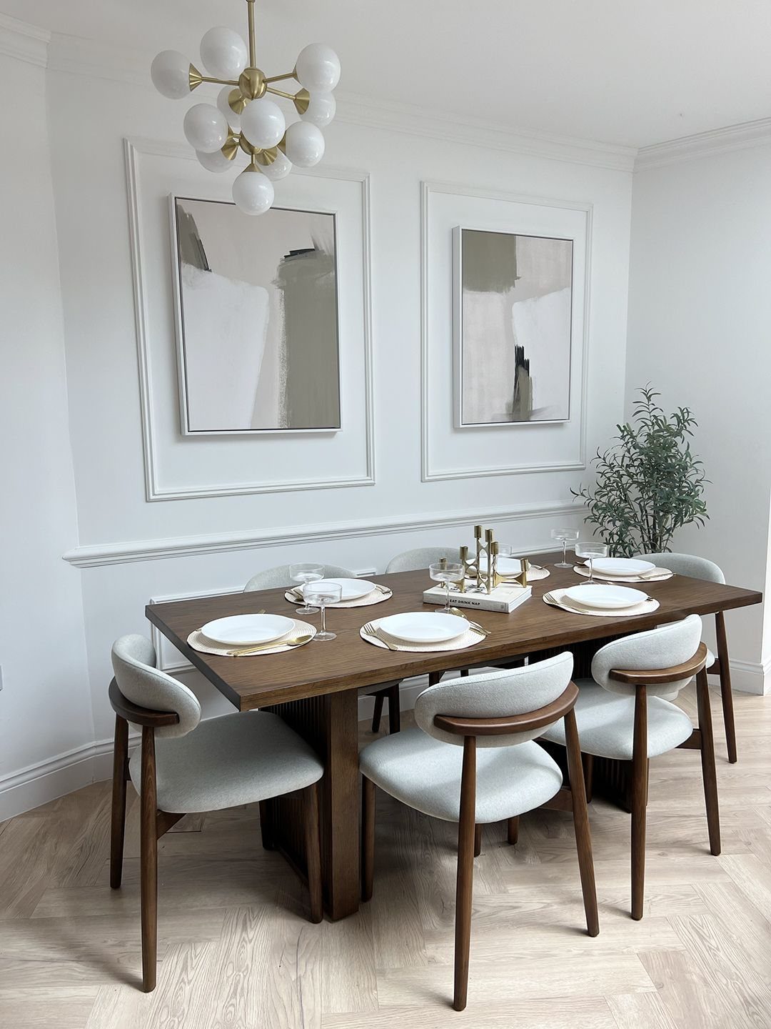 Walnut dining table with cream upholstered chairs in a bright modern dining room