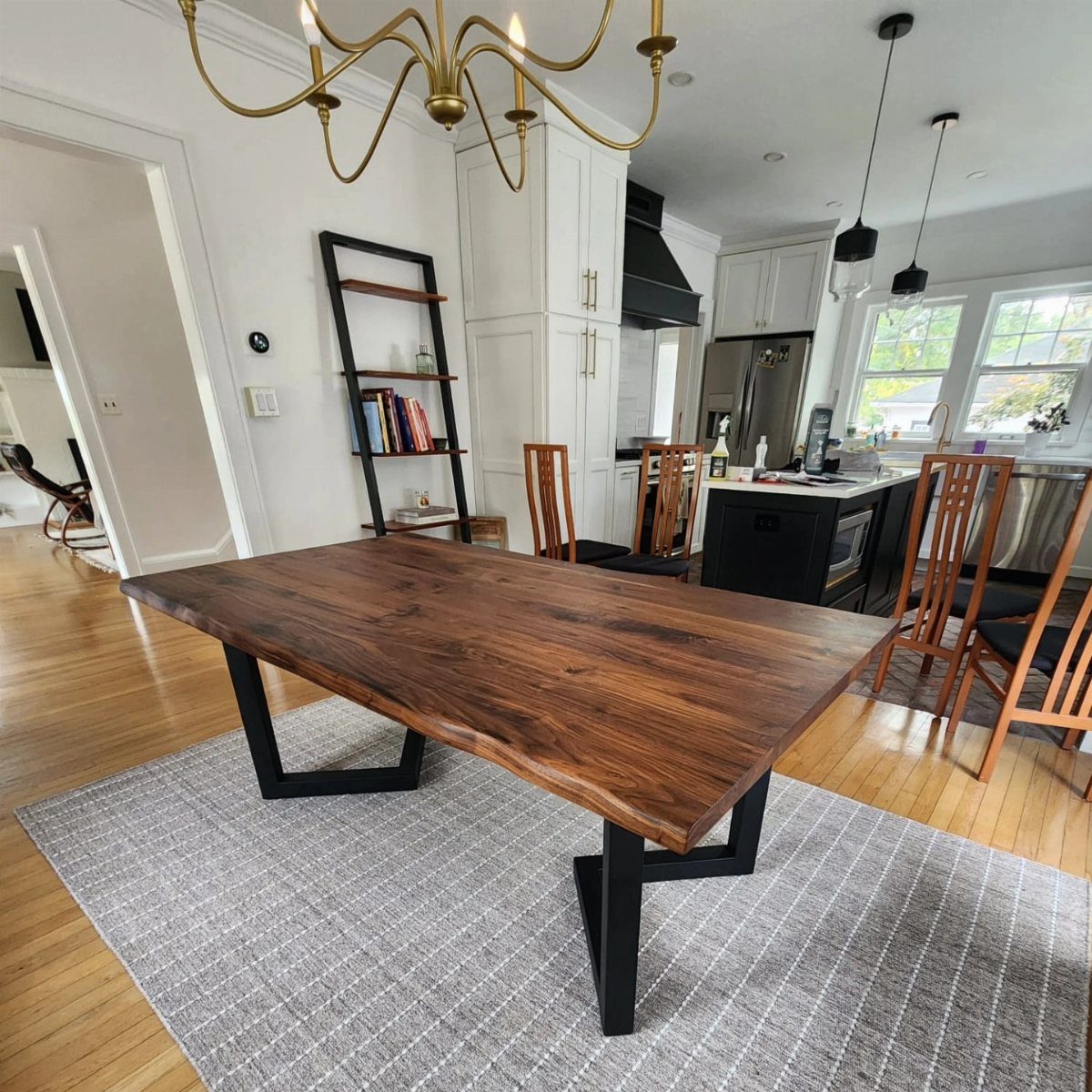 Walnut live-edge dining table with black metal legs on a grey area rug.