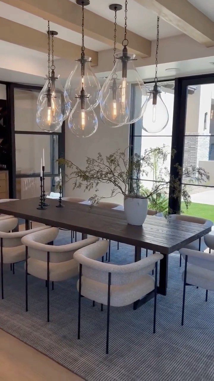 Dark walnut dining table with cream upholstered chairs and glass pendant lights above.